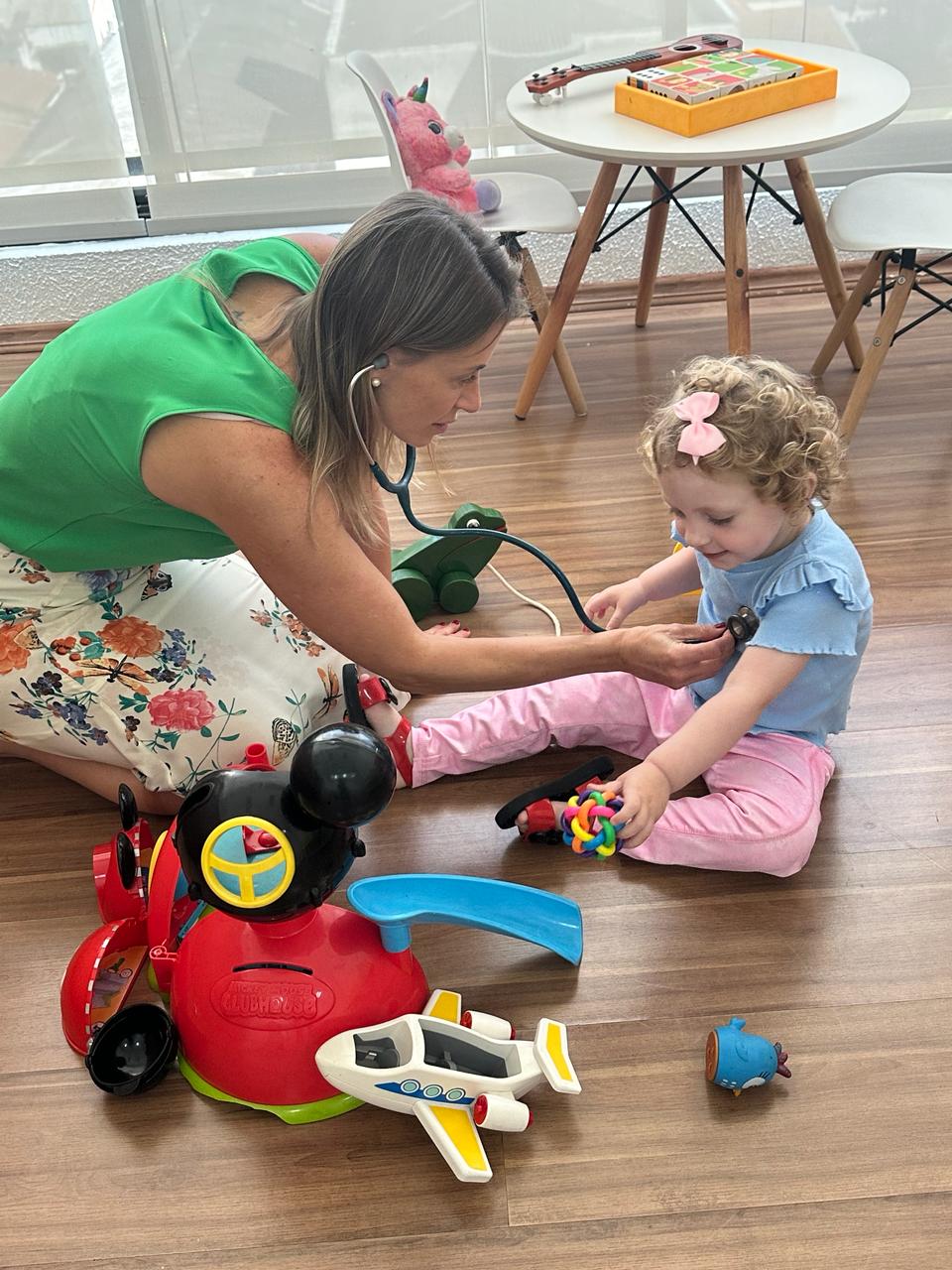 Dra. Milena brincando no chão durante consulta com criança