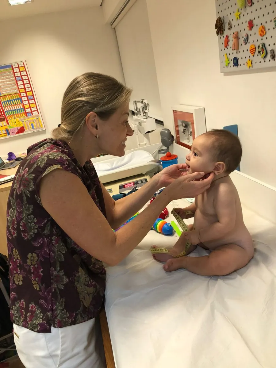 Dra. Milena conversando com bebê durante exame físico